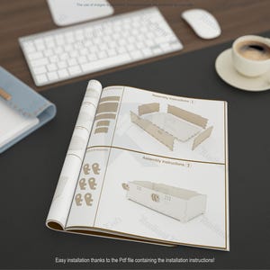 May include: Open instruction manual with assembly diagrams for a wooden product. The manual is on a dark surface, next to a keyboard, mouse, and a cup of coffee. The text reads "Assembly Instructions" and "Easy installation thanks to the Pdf file".