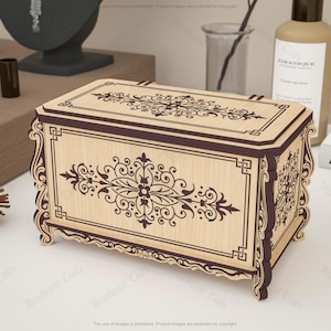 May include: A decorative wooden box with intricate floral and scrollwork designs. The box features a light wood finish with dark brown accents and a rectangular shape. The design is symmetrical and ornate, suitable for storing jewelry or small items.