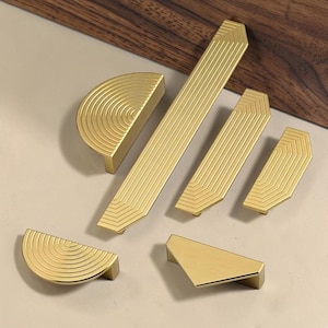 Può includere: Un set di tre tazze in ceramica con finitura opaca e macchiettata. Le tazze sono nei toni del crema, grigio chiaro e grigio scuro. Ogni tazza ha un design semplice e minimalista.