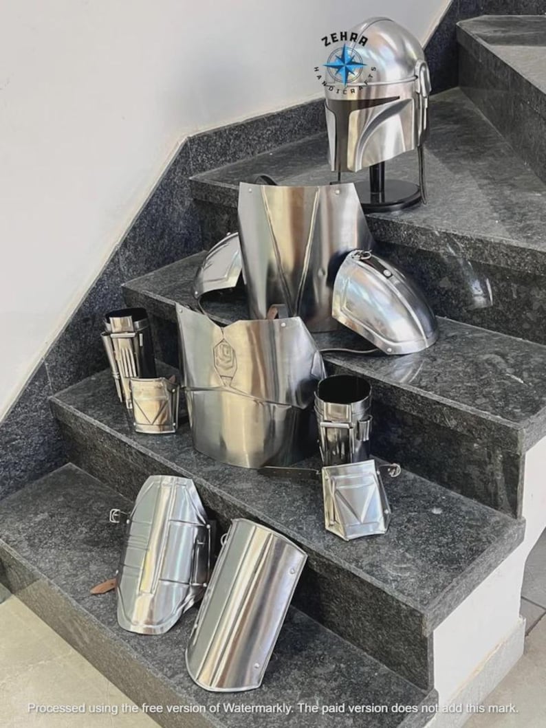 May include: A complete set of polished metal armor, including a helmet, chest plate, shoulder pads, and arm guards, displayed on a staircase. The helmet is on a black stand. The armor is silver and reflects the light.