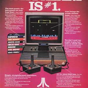 Puede incluir: Un anuncio de la consola de videojuegos Atari 2600. La imagen muestra la consola, los mandos y los cartuchos de juego. La pantalla muestra un juego. El texto dice "WHY ATARI IS #1" y destaca las características de la consola.