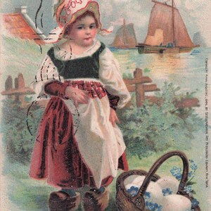 Puede incluir: Postal de Pascua vintage con un niño con vestimenta tradicional, sosteniendo una cesta de huevos. La imagen incluye veleros y el texto "Loving Easter Greeting". La postal tiene una estética nostálgica y antigua.