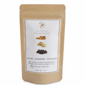 Op de afbeelding: Een bruine papieren zak met 90 plantaardige capsules van kurkuma, gember en zwarte peper. Het etiket toont deze ingrediënten, de tekst Dien Chan Emei, de vermelding 100% biologische landbouw en een nettogewicht van 65 g.