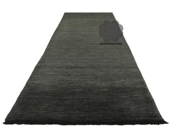 May include: A dark gray runner rug with a textured surface. The rug has a rectangular shape and a slightly frayed edge. The text "NAZMACREATIONS" is visible on the rug.