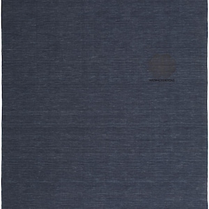 May include: A large, rectangular navy blue rug with a textured surface. The rug has a subtle, horizontal pattern and a solid colour, suitable for various interior design styles. The text "NAZMACREATIONS" is visible on the rug.