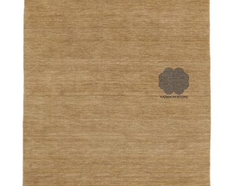 May include: A rectangular, tan-coloured rug with a textured surface. The rug has a fringe on the top and bottom edges. A decorative emblem and the text "nazmacreations" are visible near the bottom right corner.