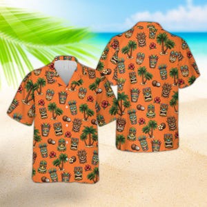 Könnte beinhalten: Orangefarbenes Hawaiihemd mit einem sich wiederholenden Muster aus Tiki-Masken, Palmen, Kokosnüssen und Blumen. Das kurzärmelige Hemd hat eine Knopfleiste und einen klassischen Kragen. Der Hintergrund deutet auf einen tropischen Strand hin.