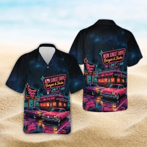 Puede incluir: Una camisa de manga corta con botones y un estampado de cielo nocturno azul oscuro con una escena de restaurante retro. El gráfico muestra un coche rosa, un edificio con el letrero Neon Sunset Drive Burger & Shake 24/7 y Moonlit Motor Club.
