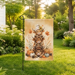 May include: A rectangular garden flag featuring a vertical stack of three fluffy Highland cows. The top cow wears a knit beanie, the middle a plaid scarf, and the bottom a plaid cap. They are surrounded by orange pumpkins, autumn leaves, and wheat.