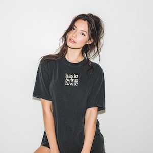 Woman wearing basic being basic minimalist black t shirt with clean aesthetic text design, soft girl neutral outfit, casual everyday tee