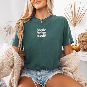 Minimalist aesthetic outfit featuring basic being basic text green t shirt, relaxed casual style with neutral cozy vibe, everyday soft girl look