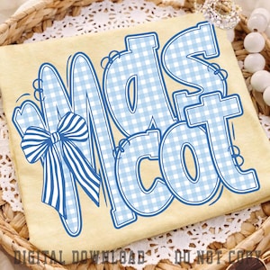 May include: A pale yellow t-shirt featuring the word MASCOT in large, light blue and white gingham patterned letters with a dark blue outline. A prominent blue and white striped bow is attached to the left side of the letter M.