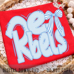May include: A bright red t-shirt featuring the text "Pet Rebels" in a large, light blue and white vertical striped font. The design includes a prominent light blue and white striped bow graphic positioned above the letter b in the word Rebels.
