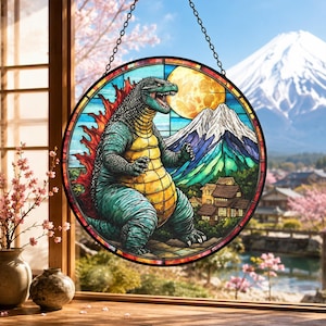 May include: A circular stained glass panel featuring a large, textured green and yellow monster with red dorsal fins standing before a full moon and a snow-capped mountain. The scene includes small traditional buildings and a blue sky background.