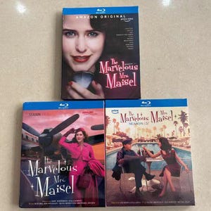 May include: A set of three ceramic mugs with a speckled, matte finish. The mugs are in shades of cream, light gray, and dark gray. Each mug has a simple, minimalist design and a rounded handle.