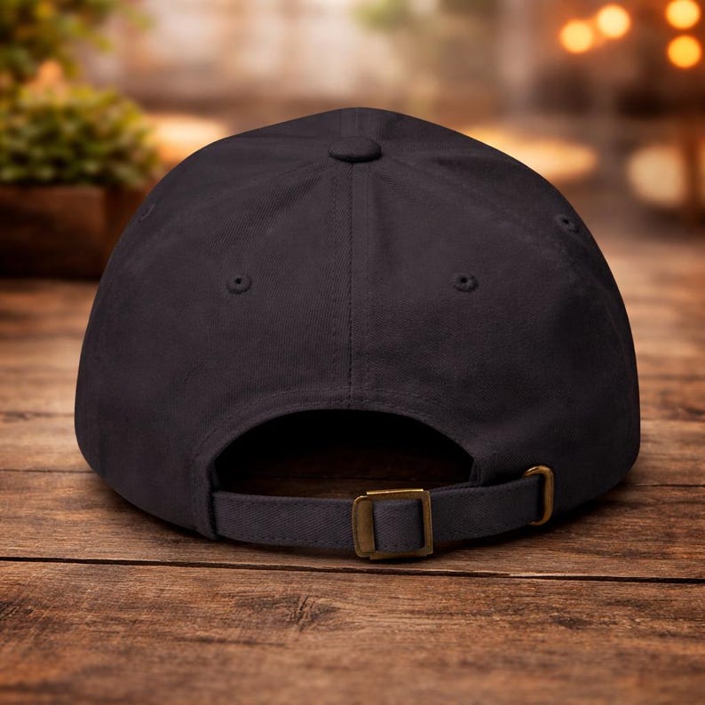 Op de afbeelding: Een zwarte baseballpet met een gebogen klep, verstelbare band en een messingkleurige gesp. De pet is gemaakt van een duurzame stof en heeft een klassiek zes-panelen ontwerp. De achterkant van de pet is zichtbaar.