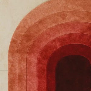 Close-up of a luxury hand-tufted silk area rug featuring concentric arch gradient bands transitioning from soft terracotta and dusty rose to deep crimson and rich burgundy. Plush velvety pile texture and precision tufting craftsmanship are clearly visible, highlighting exceptional silk quality and smooth ombre color gradation.