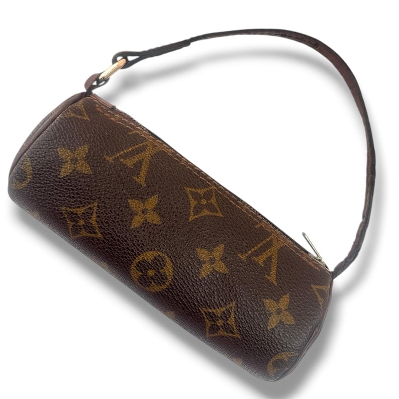 May include: A brown cylindrical handbag featuring a repeating logo pattern. It has a small brown handle and a silver zip. The bag's design is a classic style.