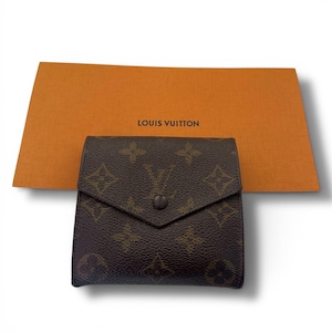 May include: A brown wallet featuring the iconic Louis Vuitton monogram pattern in a dark brown and tan color scheme with a triangular flap and a single snap button closure, positioned in front of an orange card with the text LOUIS VUITTON.