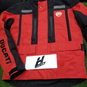May include: Red and black Ducati motorcycle jacket with the Ducati logo on the chest and sleeve. The jacket has multiple pockets, reflective stripes, and the word "DUCATI" printed on the sleeve. A white sign with the text "HOSIMAX" is in front of the jacket.