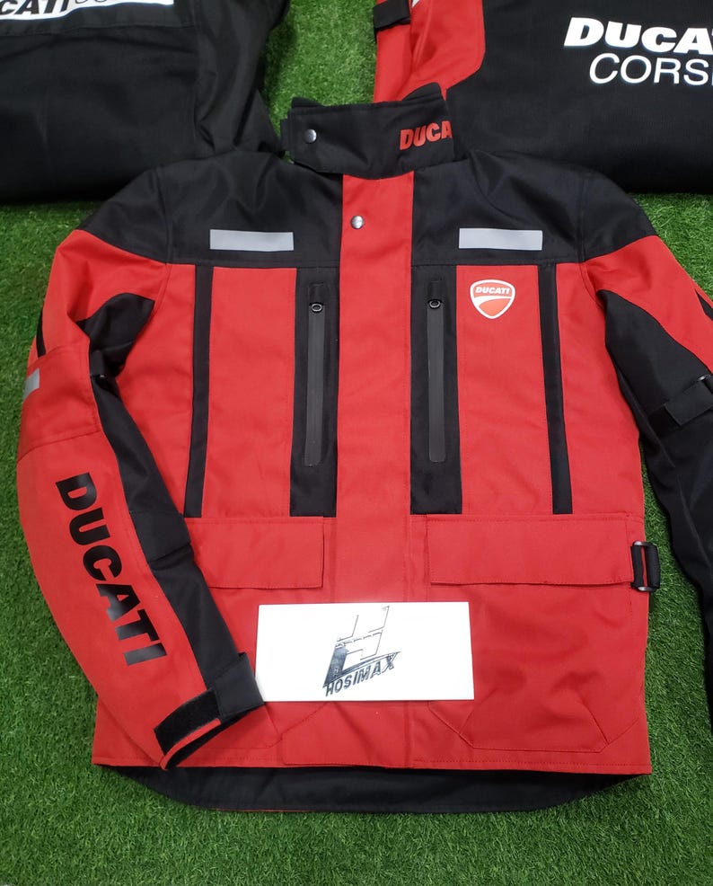 May include: Red and black motorcycle jacket with the Ducati logo on the chest and sleeve. The jacket has a high collar, multiple pockets, and reflective stripes. The word "DUCATI" is printed on the sleeve.