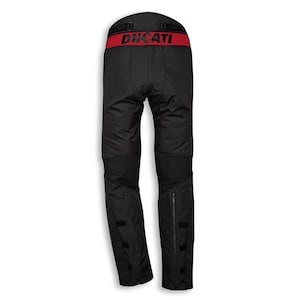 May include: Black motorcycle pants with a red waistband featuring the word "DUCATI" in red lettering. The pants have zippers at the ankles and reinforced knee areas. The pants are designed for motorcycle riding.