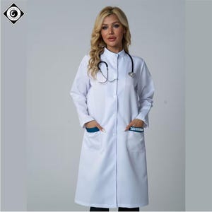 Puede incluir: Una bata médica blanca con cuello mandarín y mangas largas. La bata tiene dos bolsillos delanteros con detalles en verde azulado y un pequeño logotipo. Un estetoscopio cuelga del cuello. La persona lleva una bata con pelo rubio.