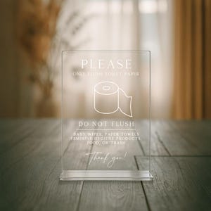 May include: Transparent acrylic bathroom sign. It features the text "PLEASE ONLY FLUSH TOILET PAPER" and a toilet paper roll graphic. Below, it reads "DO NOT FLUSH" and a list of items. The sign ends with "Thank you!"