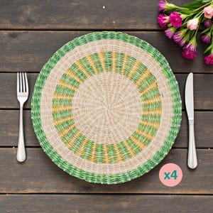 Peut inclure: Un set de table tissé avec des accents verts et jaunes, une fourchette et un couteau sont disposés sur une surface en bois foncé. Le set de table a un motif circulaire. Un petit cercle rose avec le chiffre "4" est en bas à droite. Des fleurs roses sont en haut à droite.
