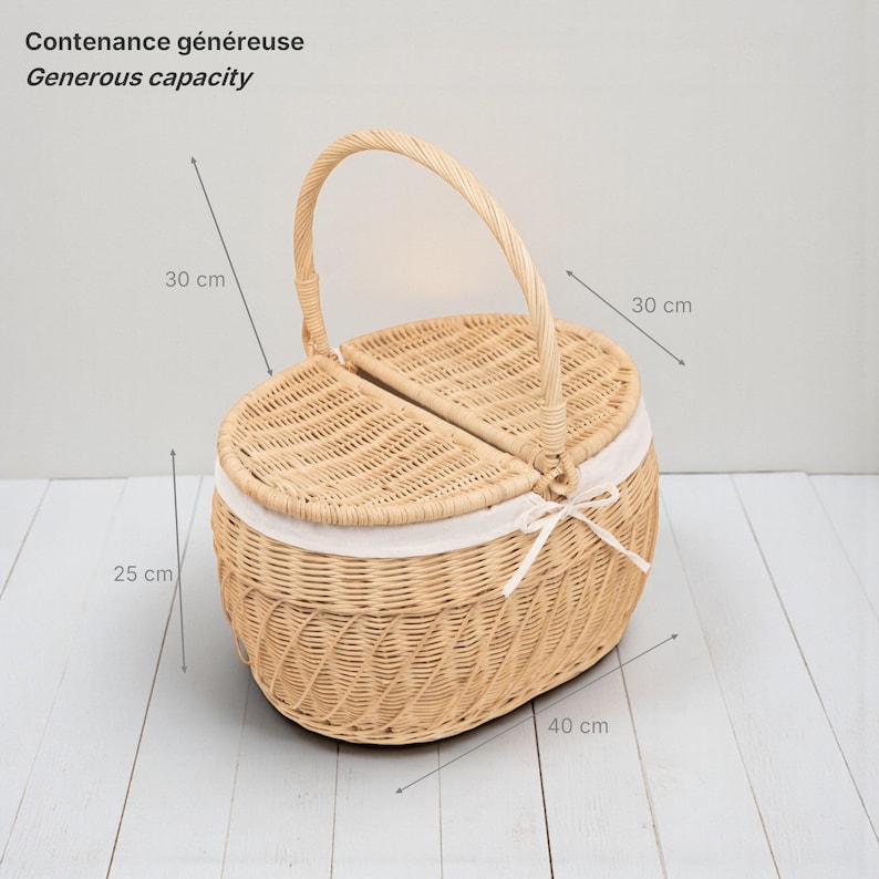 May include: Woven wicker picnic basket with a handle and two hinged lids. The basket is oval-shaped, with dimensions of approximately 15.7 inches long, 11.8 inches wide, and 9.8 inches high. It features a white fabric lining and a bow closure.