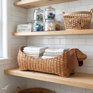 May include: A woven dachshund-shaped basket filled with folded white and beige towels sits on a wooden shelf. Above, glass jars hold laundry supplies. A wooden sign reads "Teckel Laundry Co." A wooden basket and shelves complete the laundry room scene.