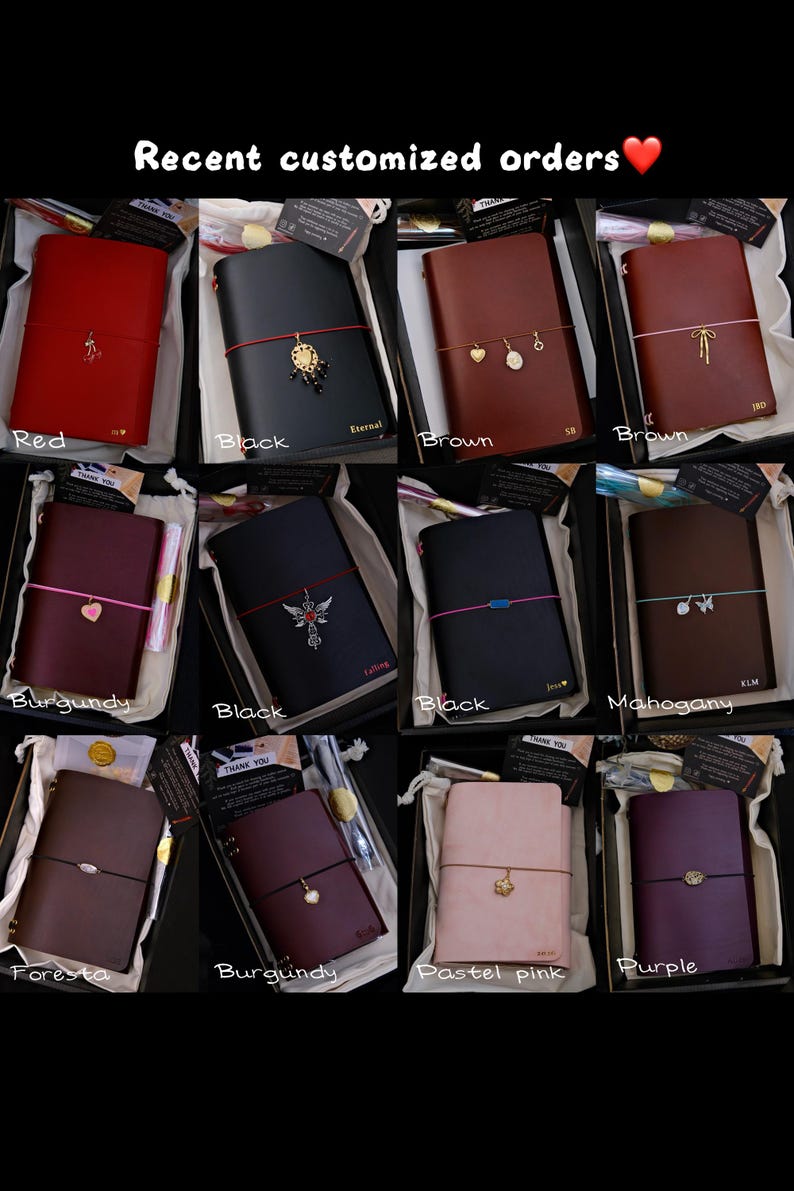 May include: A collection of twelve rectangular leather journals in various colours including red, black, brown, burgundy, mahogany, foresta, pastel pink, and purple. Each journal features a coloured elastic band with a unique metal charm attached.