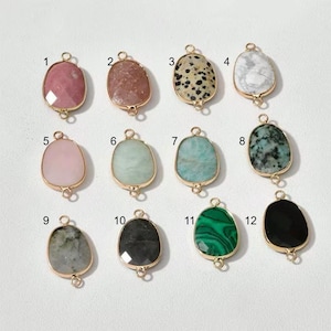 Può includere: Una collezione di dodici ciondoli con pietre preziose in vari colori e motivi, ciascuno con una cornice in metallo color oro e un anello per il fissaggio a una catena o ad un altro componente di gioielleria. Le pietre preziose includono rosa, marrone, maculato, bianco, verde e nero.