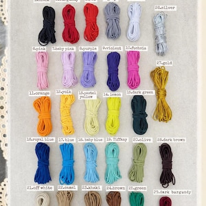May include: A collection of 29 bundles of elastic cord in various colours, labelled with numbers 1 through 29. The colours include black, burgundy, red, grey, white, silver, pink, purple, fuchsia, gold, orange, yellow, green, blue, and brown.