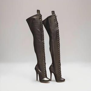 “High heel lace-up knee boots with 14cm stiletto heel and round toe design on clean studio background.”