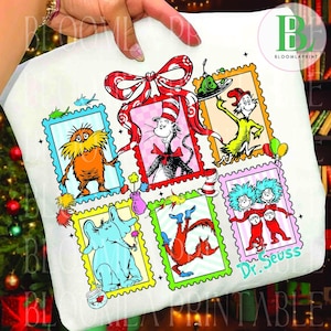 May include: White t-shirt featuring colorful illustrations of Dr. Seuss characters in postage stamp frames. The design includes The Cat in the Hat, The Lorax, and Thing 1 and Thing 2, with the text "Dr. Seuss" in a teal script.