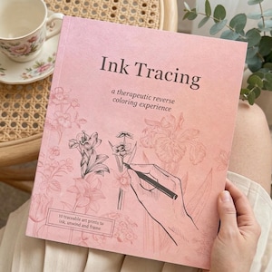 May include: A pink coloring book titled "Ink Tracing" with floral illustrations and the text "a therapeutic reverse coloring experience." The book features a hand drawing a flower with a pen. The text "10 traceable art prints to ink, unwind and frame" is also visible.