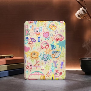 May include: A cream-coloured rectangular portable charger with a vibrant cartoon design. The design incorporates cartoon characters, stars, hearts, and letters in pink, blue, yellow, and green. The charger is positioned on a dark surface.