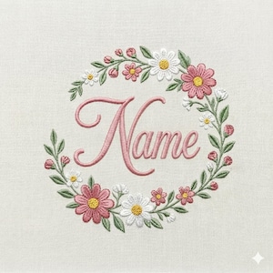 Pode incluir: Grinalda floral bordada com a palavra "Name" em um delicado script rosa. A grinalda apresenta flores rosa e brancas com centros amarelos, folhas verdes e pequenos botões rosa, tudo sobre um fundo de tecido creme.