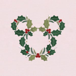 Könnte beinhalten: Gesticktes Design eines Mickey Mouse-Kopfes aus grünen Stechpalmenblättern und roten Beeren auf hellrosa Hintergrund. Das Design ist eine festliche Weihnachtsdekoration.