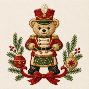 May include: An embroidered design of a tan teddy bear dressed as a toy soldier in a red uniform with gold accents, playing a green and gold drum. The bear is flanked by green pine branches, red berries, and two decorative Christmas ornaments.