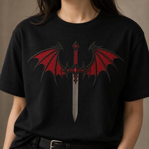 Könnte beinhalten: Schwarzes T-Shirt mit einem gestickten Design eines Schwertes und roten Drachenflügeln. Das Schwert hat eine silberne Klinge und einen roten Griff. Die Flügel sind tiefrot mit schwarzen Umrissen. Das Design ist mittig auf der Vorderseite des Shirts platziert.