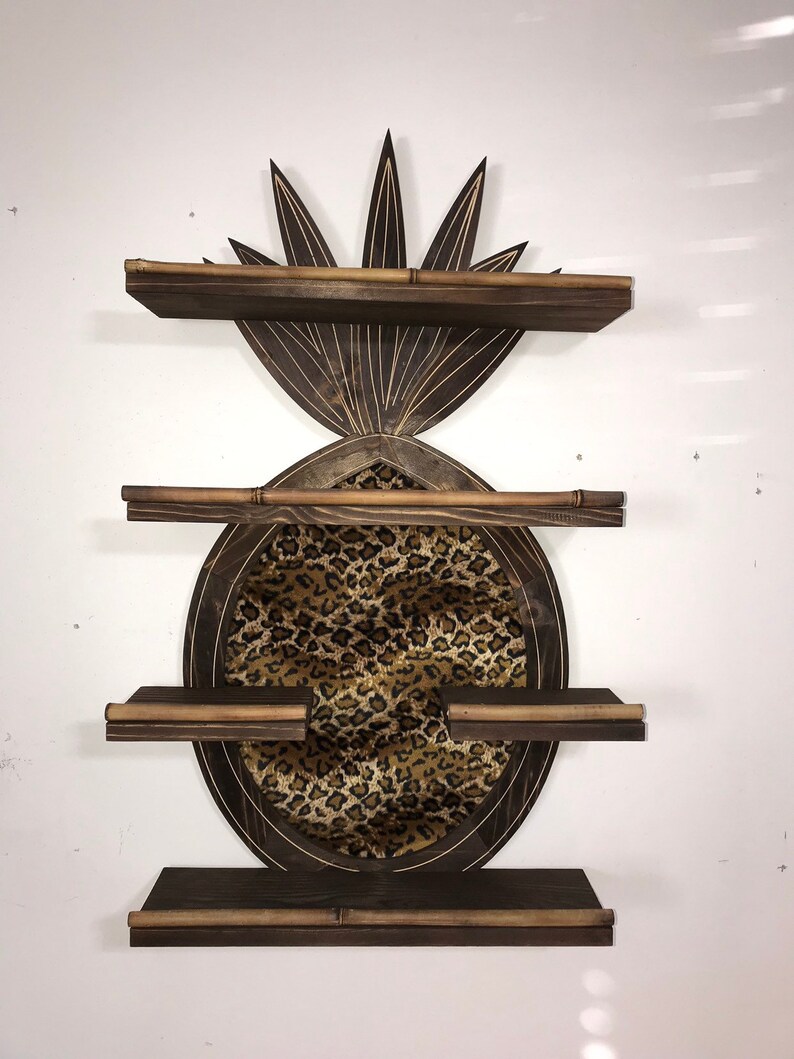 May include: A wooden pineapple-shaped shelf unit with three shelves. The shelves are made of dark brown wood and have a light brown trim. The pineapple is decorated with a leopard print fabric.