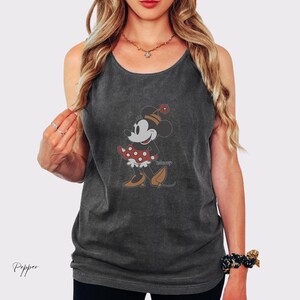 Peut inclure: D&eacute;bardeur gris fonc&eacute; avec un motif Minnie Mouse de style vintage. Le personnage de dessin anim&eacute; est repr&eacute;sent&eacute; dans une robe &agrave; pois rouges et blancs, des chaussures marron et un chapeau assorti avec une fleur. Le mot "disney" est imprim&eacute; en dessous.
