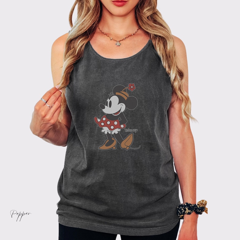 Peut inclure: D&eacute;bardeur gris fonc&eacute; avec un motif Minnie Mouse de style vintage. Le personnage de dessin anim&eacute; est repr&eacute;sent&eacute; dans une robe &agrave; pois rouges et blancs, des chaussures marron et un chapeau assorti avec une fleur. Le mot "disney" est imprim&eacute; en dessous.