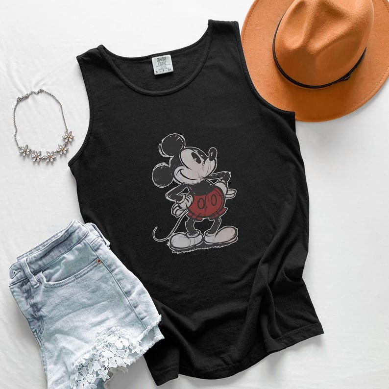 May include: A black sleeveless tank top featuring a distressed graphic of Mickey Mouse in red shorts and white shoes. The shirt has a round neckline and a tag at the collar. The design is centered on the front of the garment.