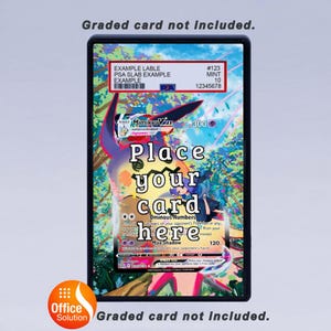 May include: A black card holder with the text "Place your card here" over a colorful Pok&eacute;mon card. The holder has a label with the text "EXAMPLE LABLE" and "PSA SLAB EXAMPLE". The text "Graded card not included" is also present.
