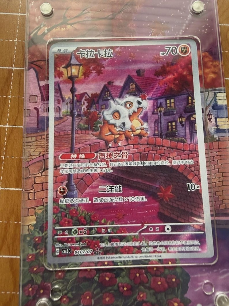 May include: A Pok&eacute;mon trading card featuring two Cubone characters on a bridge with a scenic background. The card has Japanese text and a HP of 70. The card is encased in a clear protective sleeve.