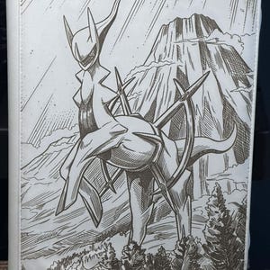 May include: White binder featuring a detailed black and white illustration of a creature with a mountain backdrop. The artwork depicts a stylized figure with sharp features and a mountainous landscape.