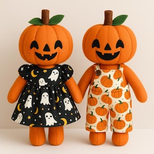 Puede incluir: Dos muñecos de peluche con forma de calabaza, cabezas naranjas, tallos marrones y hojas verdes. Uno viste un vestido negro con fantasmas blancos, lunas amarillas y estrellas. El otro lleva un peto blanco con estampado de calabazas y botones.